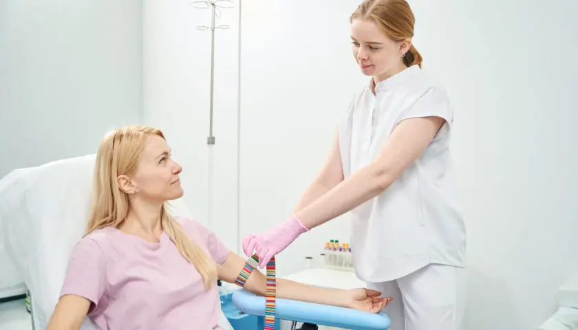 Pielęgniarka zakłada opaskę uciskową na ramię pacjentki przed pobraniem krwi na czczo.