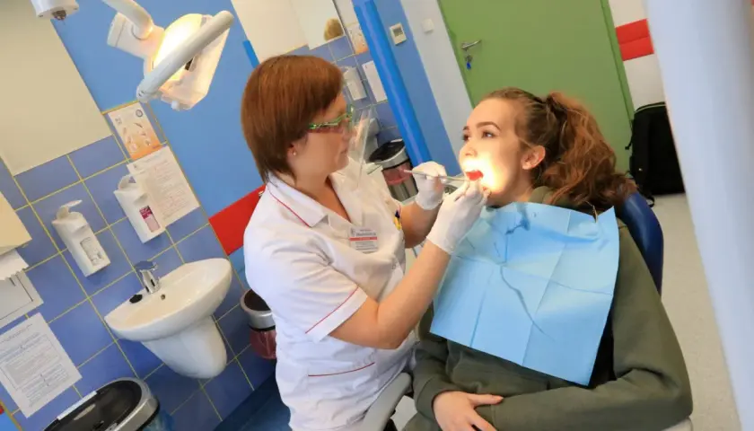 Dentystka bada zęby młodej pacjentki w gabinecie stomatologicznym.